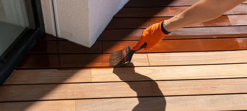 deck sealing, worker hand applying a wood stain