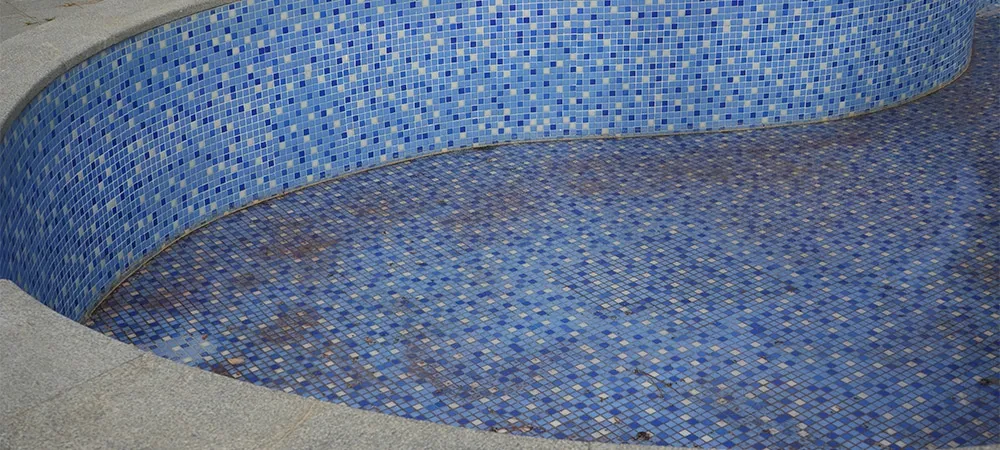 bottom of dirty leaking swimming pool removing water so the pool can be repaired