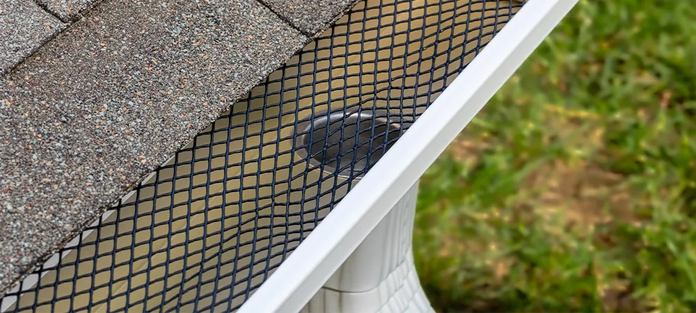 installing gutter guard mesh screen on rain guttering. home maintenance, yardwork and roof damage concept
