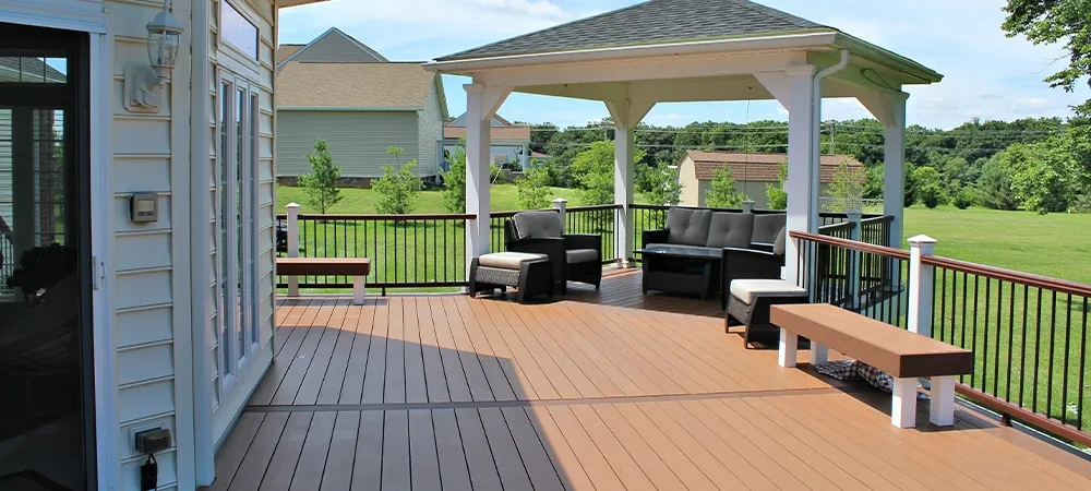 Brown composite deck with white gazebo and outdoor furniture, perfect for backyard relaxation.