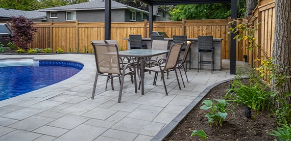 pool with patio, open kitchen, wooden fence and landscaping in yard