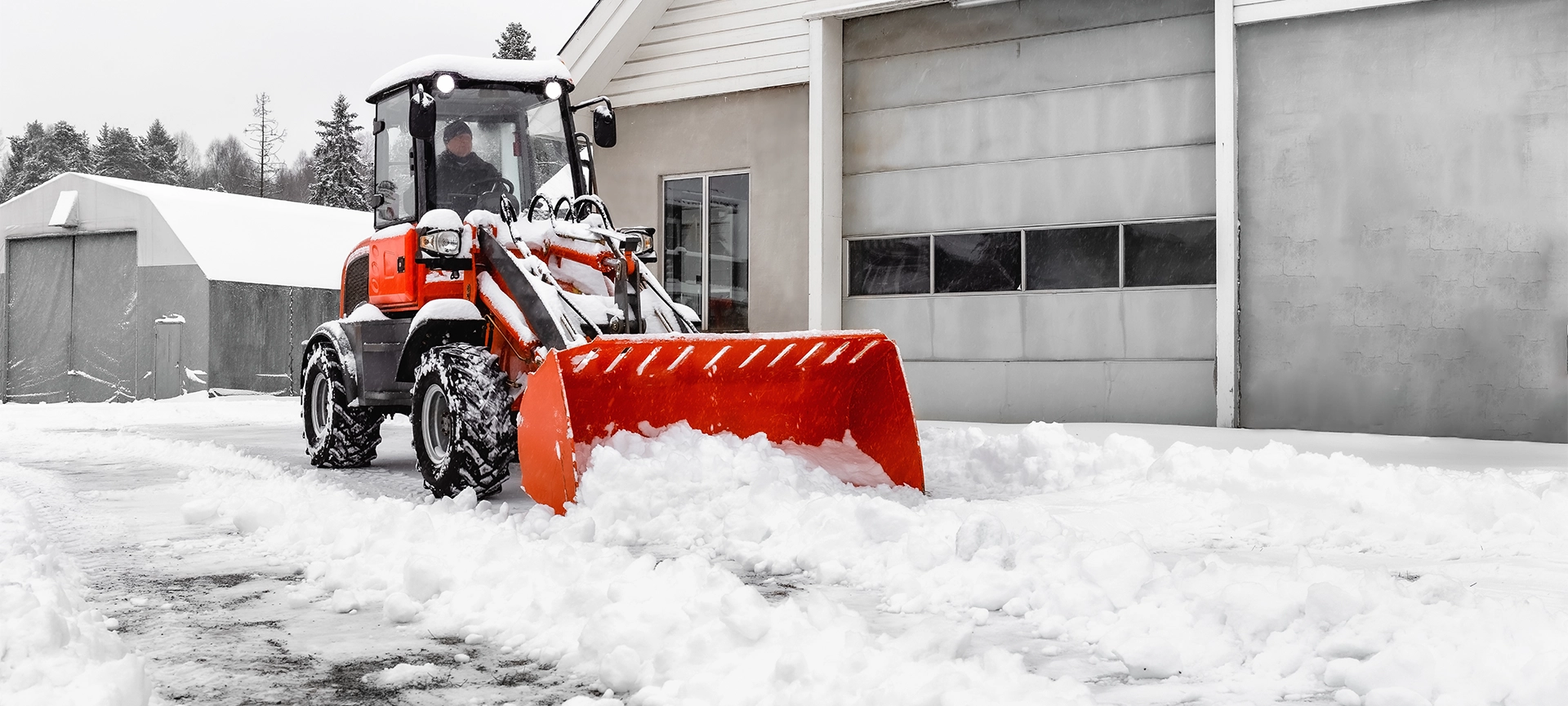 Little red tractor with snowplow in a motion removing snow