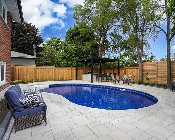 Pool interlock restoration image five pool with interlock surface in backyard, open kitchen, water drainage system, wooden fence covered full yard with landscaping