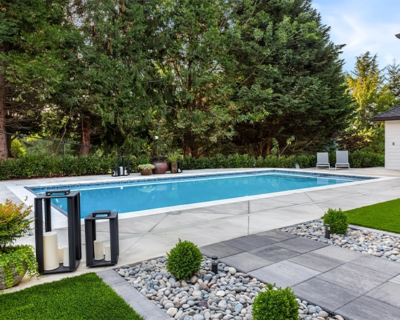 concrete pool with patio, landscaping and sodding around backyard