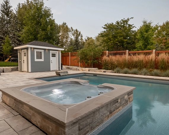 concrete pool with waterfall in home backyard, custom carpentry, interlock deck and fence