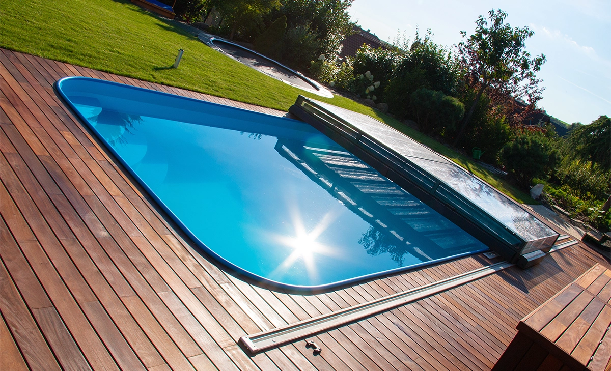 fibreglass pool with wooden deck and pool cover in garden yard