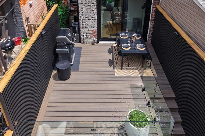 top view of backyard deck with privacy screen, fence, glass railing, steps and seating area