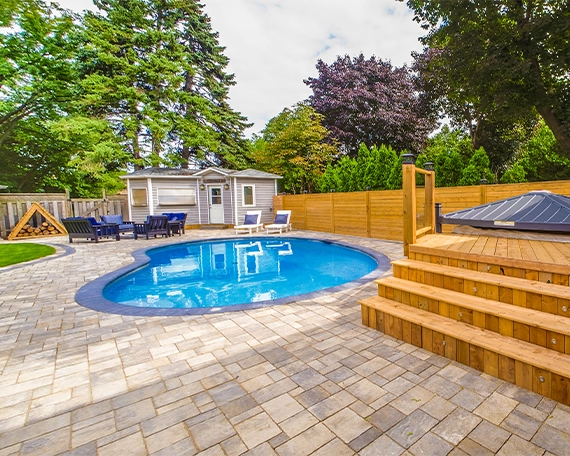 hardscaping image one interlocking patio and surface around pool with sodding, wooden deck, fence and carpentry