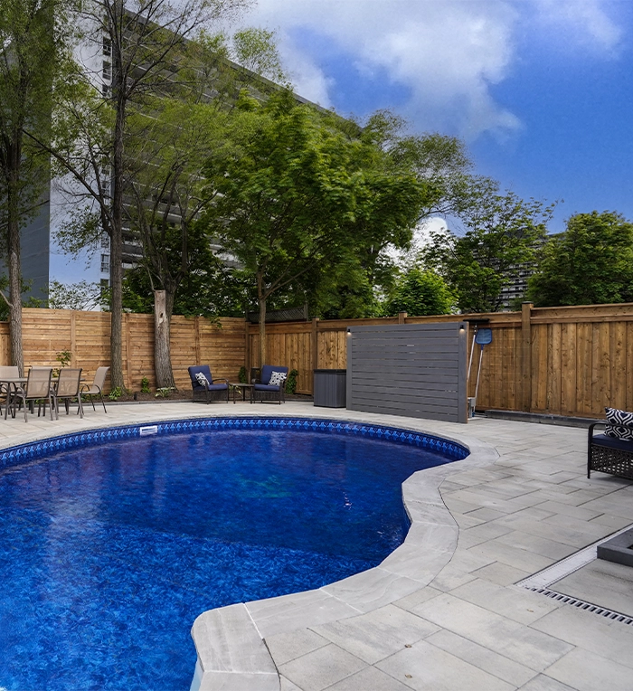 interlocking pool deck surface around swimming pool with water drainage system in backyard