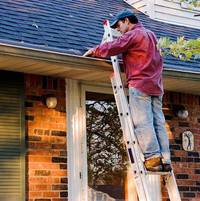 Man Cleaning Gutters on Ladder