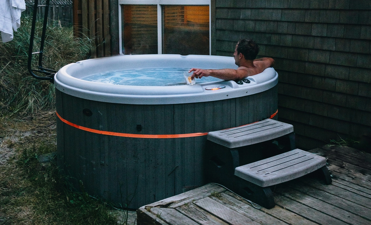 man relaxing in hot tube, in home outdoor space