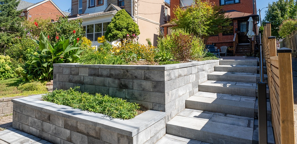 multi level interlocking blocks retaining wall with steps and fence on side in front of home
