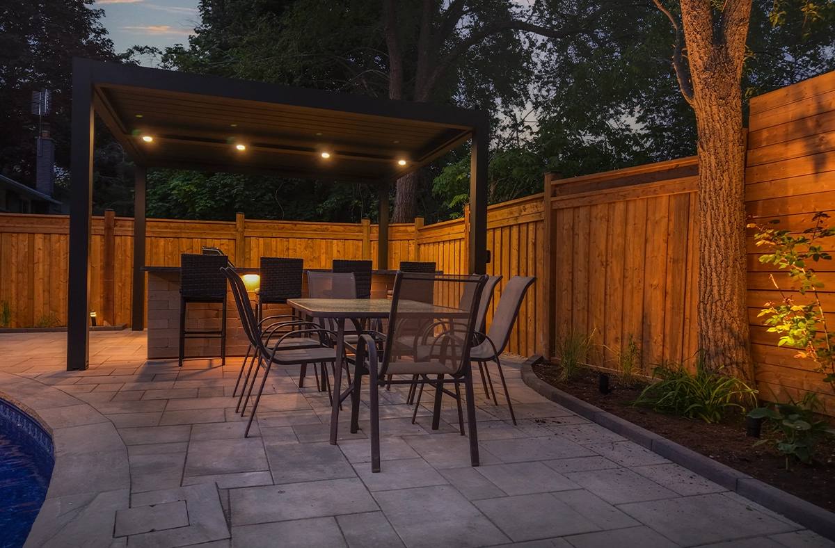 backyard space, covered outdoor kitchen with lighting feature, landscaping and fence