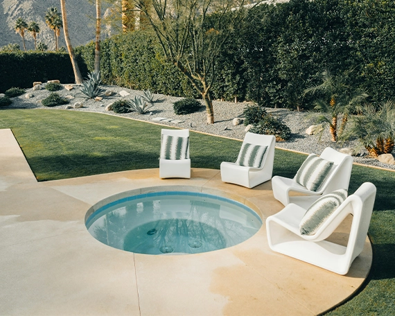 plunge pool with concrete deck, chairs around pool, in yard