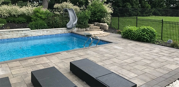 interlocking surface around pool and aluminium fence in backyard