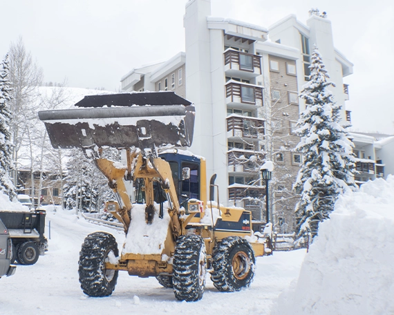 snow removal truck clearing snow in front of condo building road