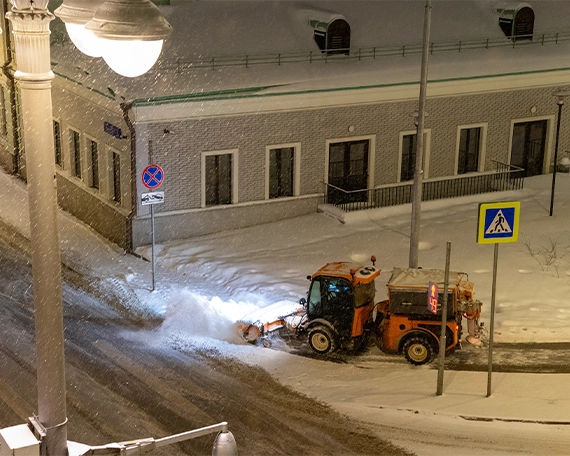 snow removal tractor clearing snow from road at night