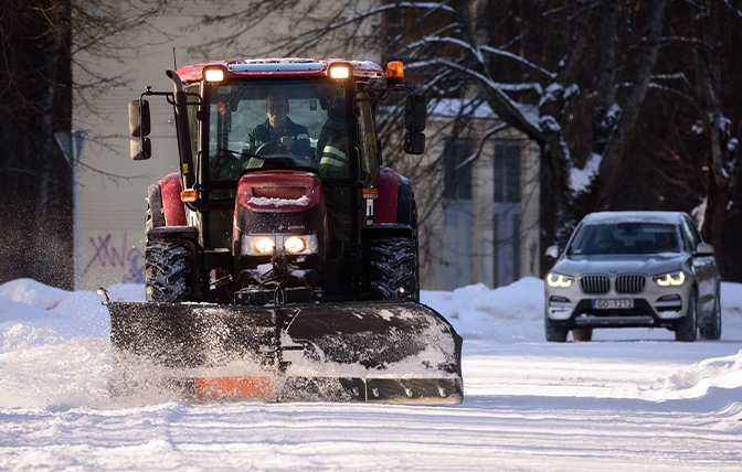 man on snow removal tractor clearing snow from road