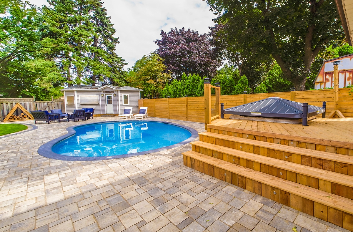 interlocking patio and surface around pool with sodding, wooden deck, fence and carpentry