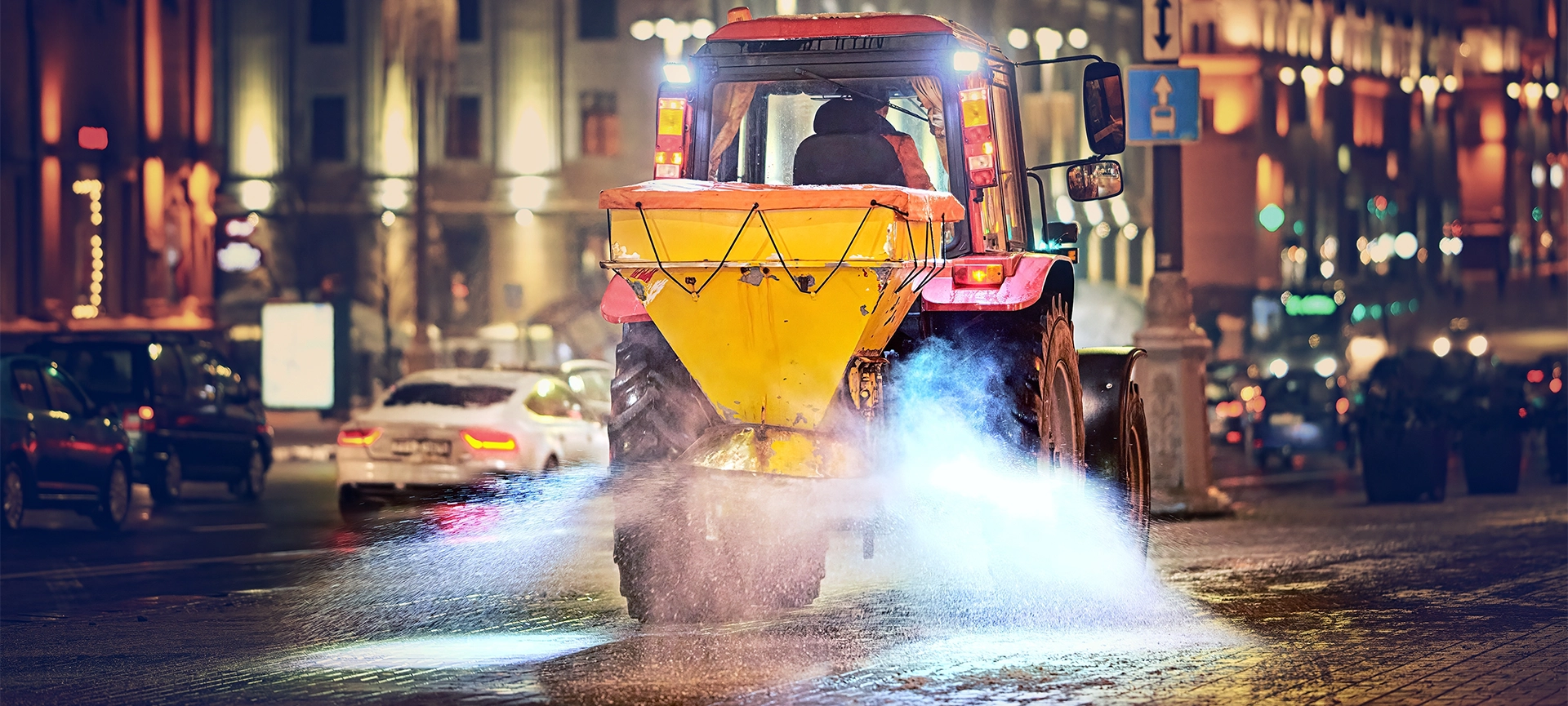 Tractor with salt spreader plow snow, spread salt on pavement after snow storm, road maintenance - winter gritter vehicle. Tractor de-icing street, spreading salt. Machinery spreader salting sidewalk