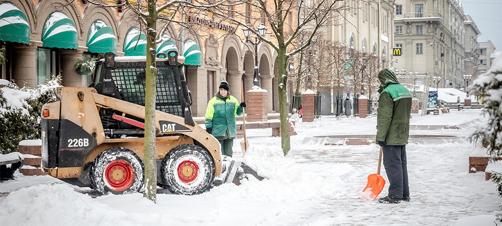 workers and snow machines remove snow in the city center after a snowfall