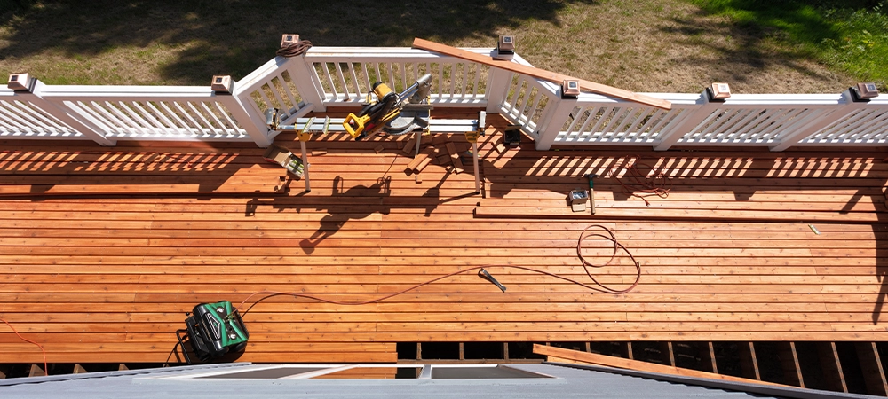 Overhead view of outdoor wooden deck being remodeled with power and hand tools on floor boards