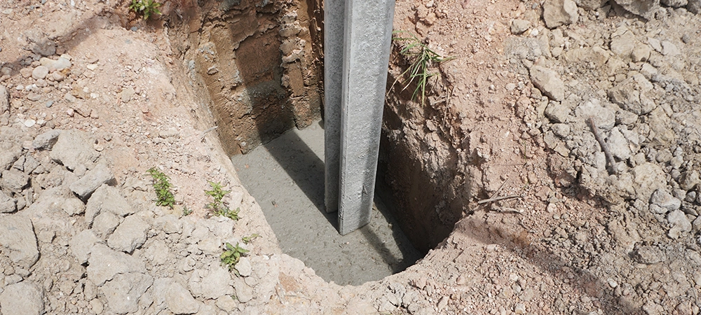 Concrete footings and i beam concrete pile for fences that are installed in hole on construction site.