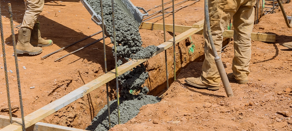 Process of pouring concrete trenches to serve as the foundation a building in construction site