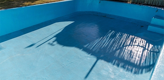 Portion of a fibreglass lined empty resort swimming pool. Concept for fixing cracks in old pools with a fibreglass lining.
