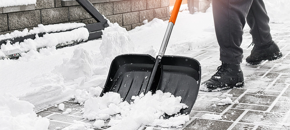 Man cleaning snow from street in winter with shovel after snowstorm.