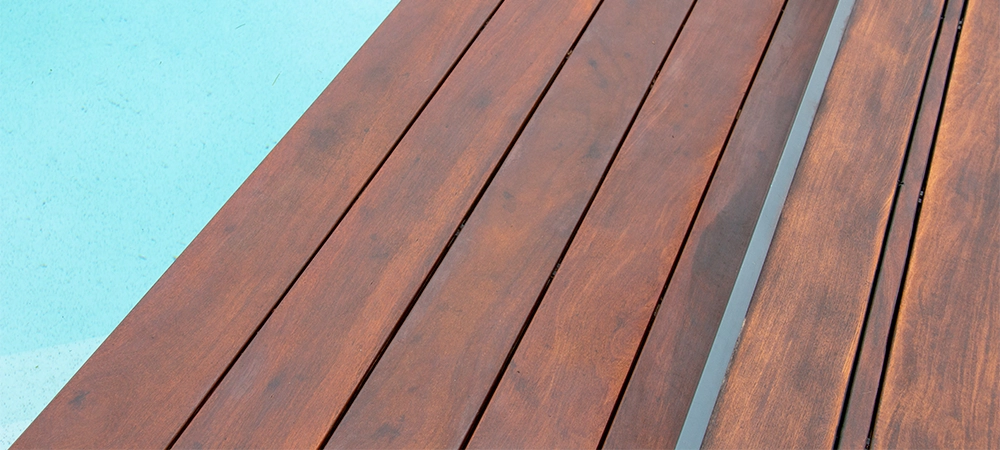 Detail of swimming pool coping and cover constructed by cumaru wood deck, hardwood decking texture next water