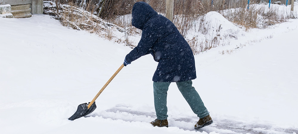 an unrecognizable man cleans snow with a shovel in a snowfall. close-up