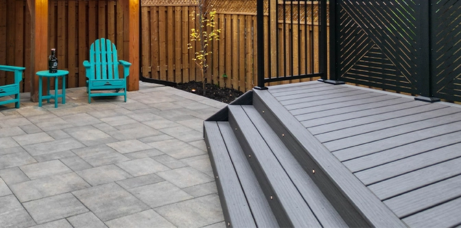 deck with lighting in steps in backyard, privacy screen, railing, interlock floor, wooden fence