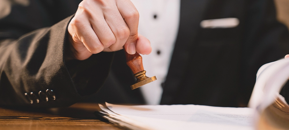 A seal to show approval of an agreement or contract by an authorized person. A businesswoman is about to stamp a document at the office legally. The boss signs the certificate or letter on the desk.