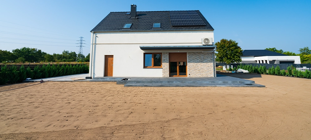 Rear side of the new build house with solar panel installation, ceramic terrace and levelled ground prepared for grass seeding
