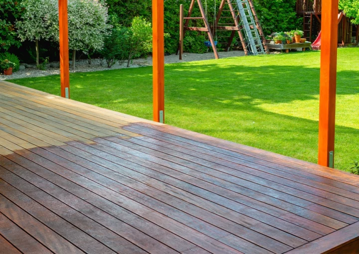 Close-up of a wooden deck - on the covered terrace - showing the process of restoration with a half-stained surface contrasting weathered and treated wood during a home improvement project