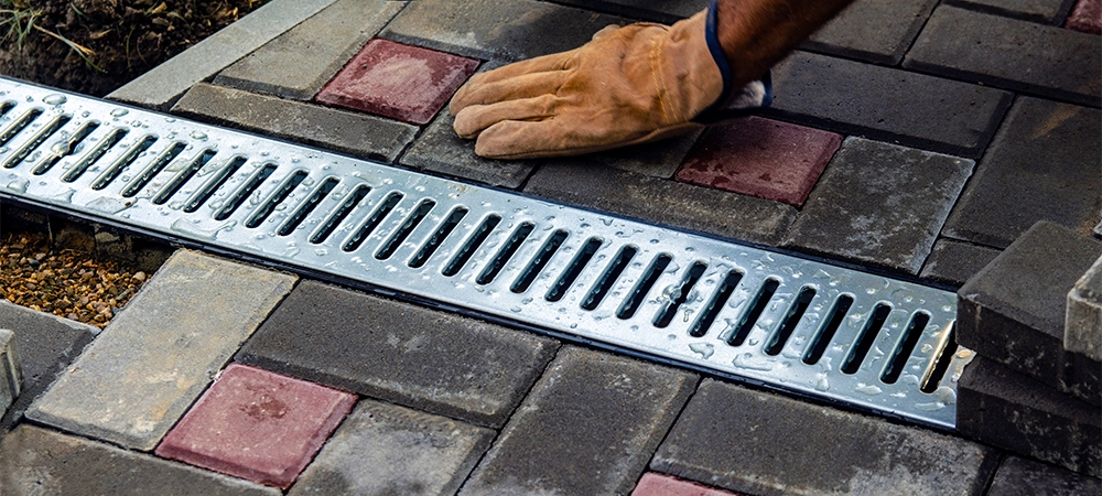 Installation of iron drainage system and paving slabs. a close-up of an iron grating along the sidewalk. Selective focus.