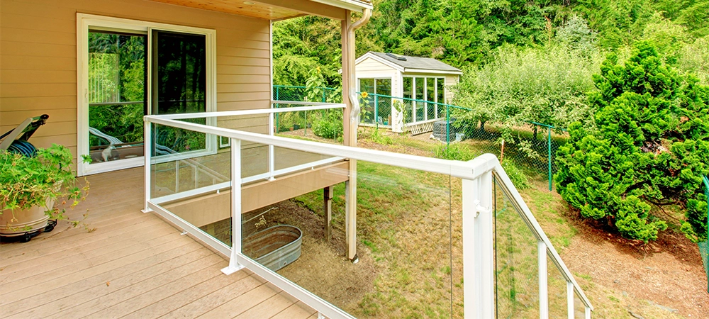 Walkout deck with glass railing. View of backyard with small shed