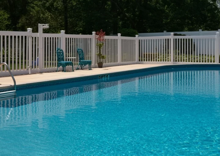 Outdoor photo of white vinyl fence around pool