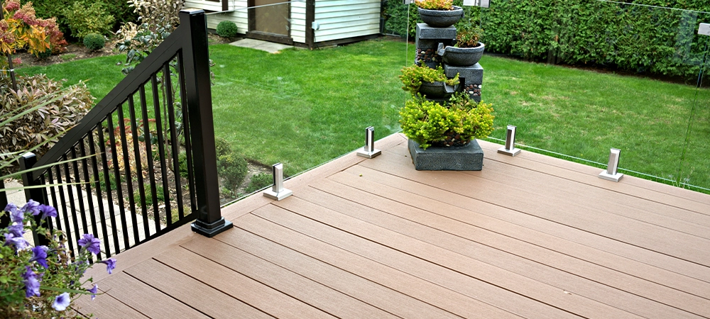 Durable deck solution with composite boards and glass panels as railings on residential home improvement project.